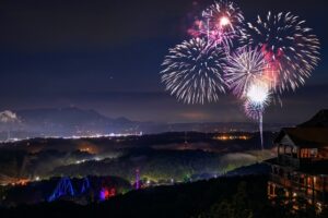 An overlook of a fireworks show over Dollywood Theme Park.