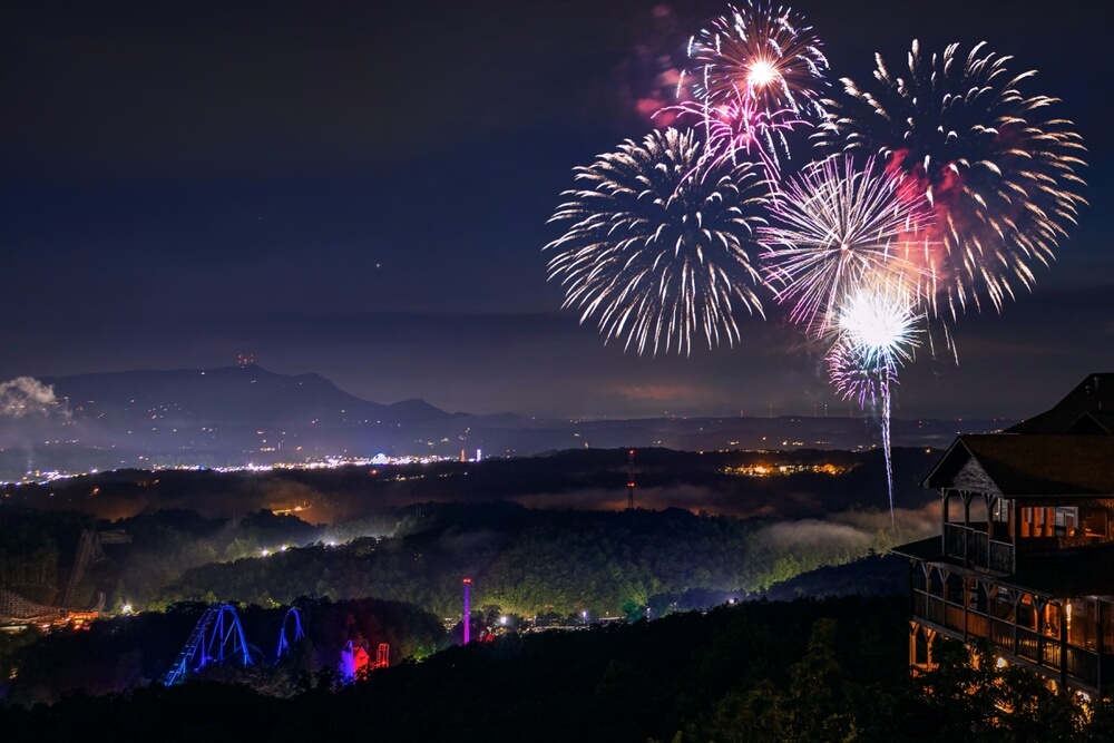 An overlook of a fireworks show over Dollywood Theme Park.