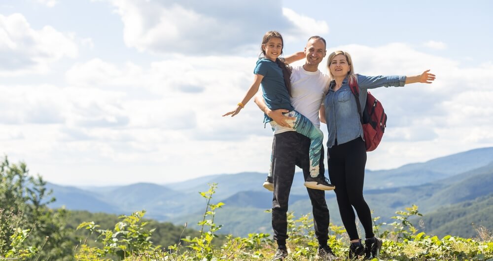 Family-Friendly Vacation Ideas Before Peak Summer: A family at the peak of a mountain overview
